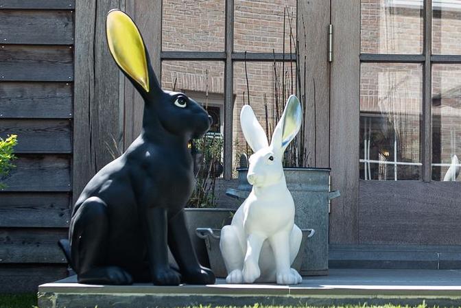 Statuen von zwei modernen Hasen in Schwarz und Gold und Weiß und Silber auf einer Terrasse Garden ID