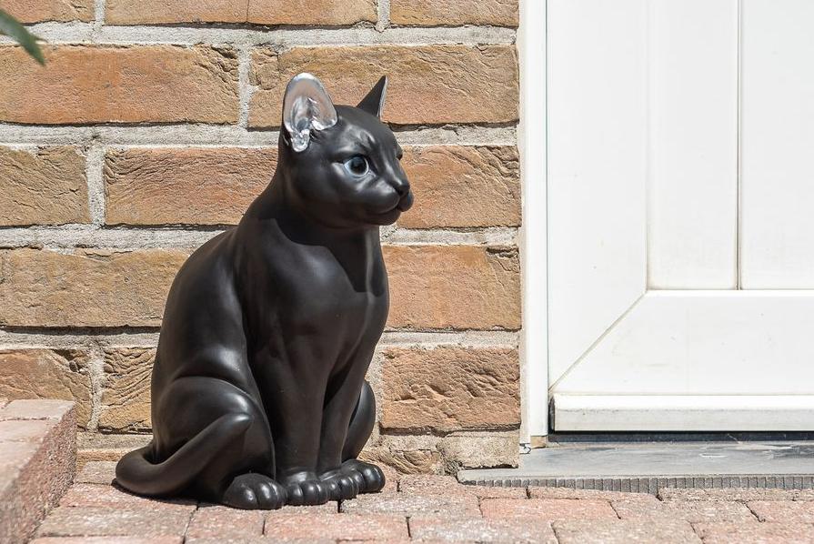 Statuen einer modernen schwarz-silbernen Katze, die neben einer Tür steht Garden ID