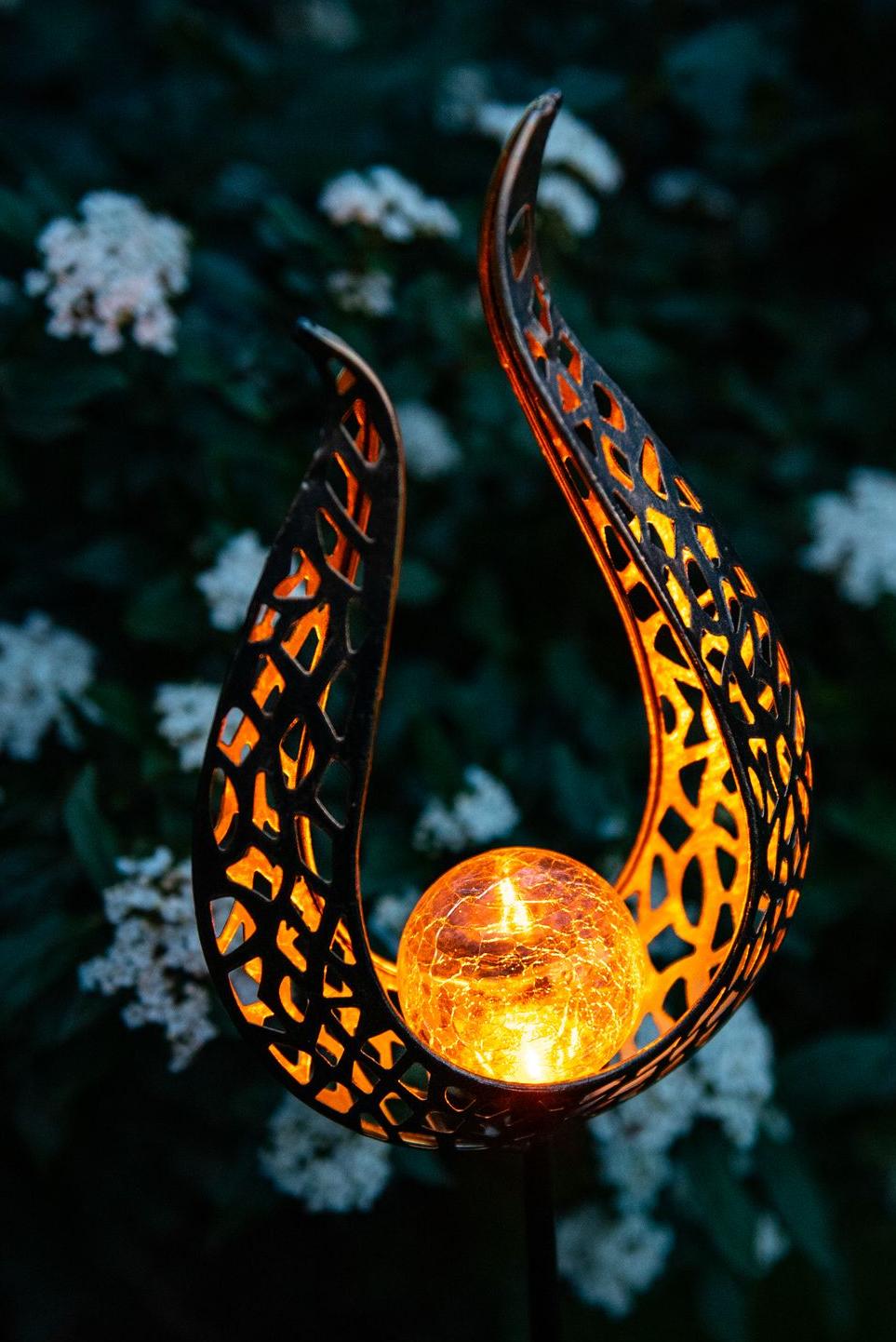 Decorative solar lamp on stake in the shape of an open flame with a glass ball emitting an orange color with a fiery effect. Garden ID
