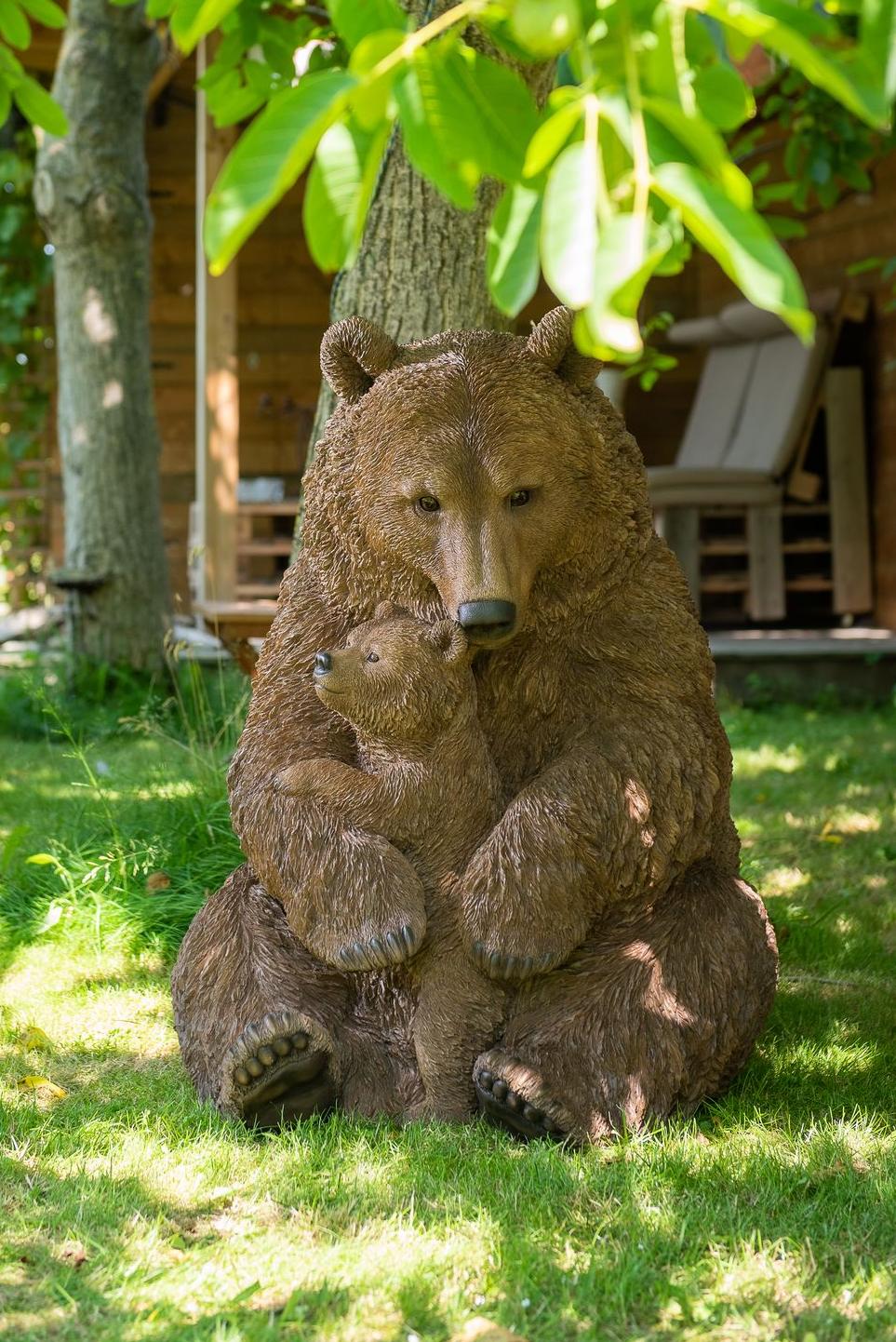 A hyper-realistic statue of a mama bear with her baby under a tree in a garden Garden ID